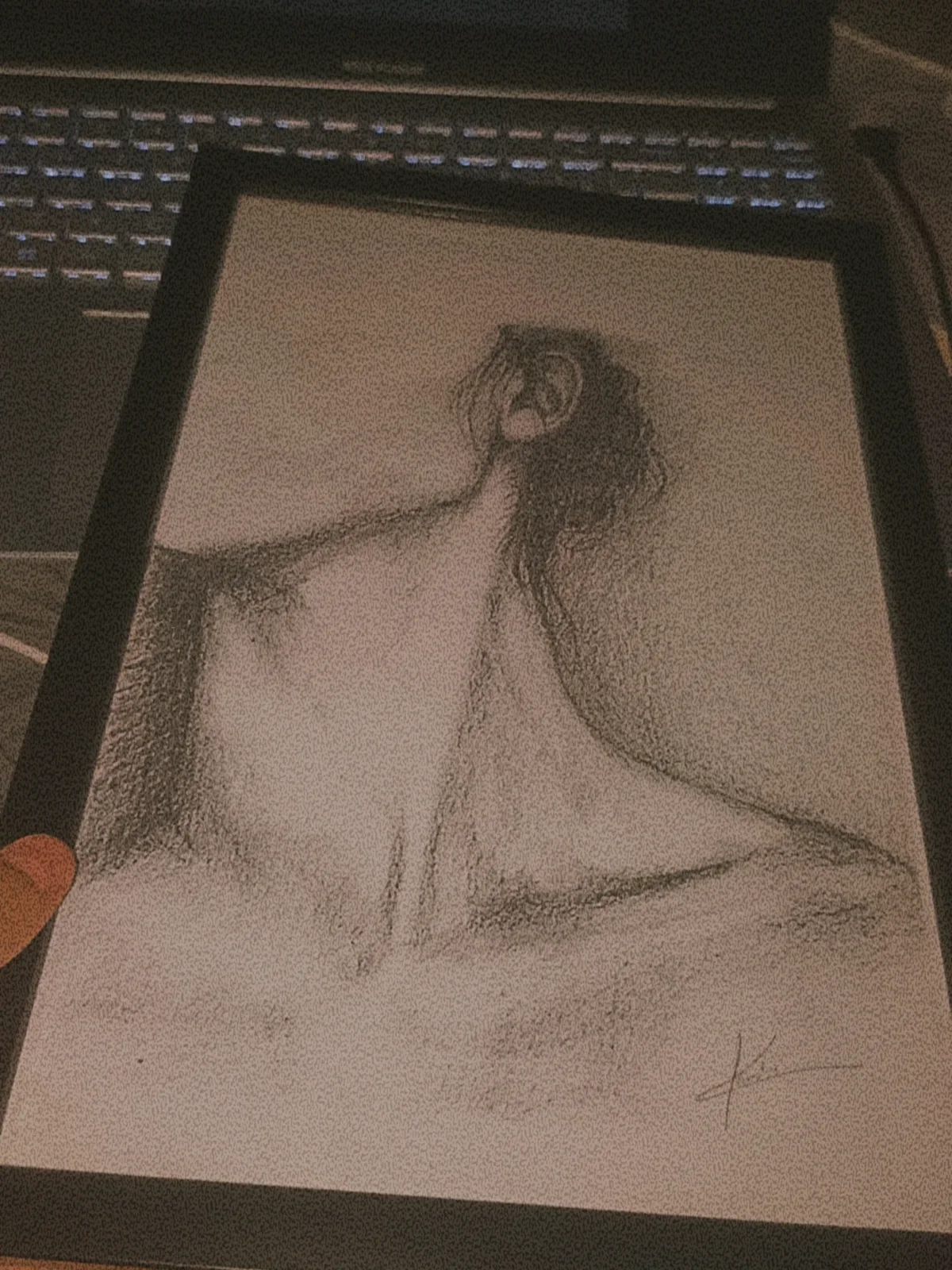 A charcoal figure study in a black frame at the drawing desk